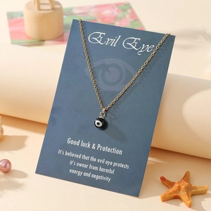 Detail of golden stainless steel evil eye pendant necklace on a blue decorative card