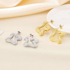Irregular wave pattern stud earrings in gold and silver finish on a satin background