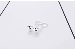 Macro shot of minimalist high-polish S999 sterling silver round ball stud earrings
