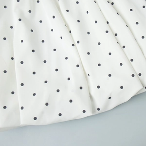 Detailed view of white polka dot fabric with soft pleats on a stylish two-piece set