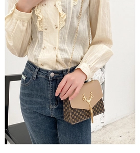 Detail of elegant chain crossbody bag featuring gold deer charm and tassel decoration