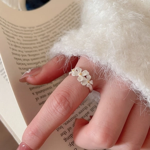 Close-up of matte silver flower ring with yellow stamens worn in a lifestyle scene