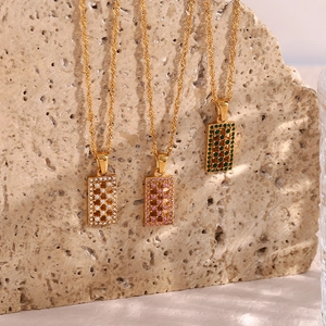 Close-up of golden hollow rectangular maze pendants with colorful zircon stones on stone