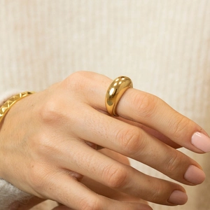 Close-up of a chunky golden dome ring and matching bracelet on a knit sweater background