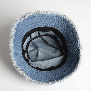 Inside view of a light blue denim bucket hat with frayed edges and adjustable straps