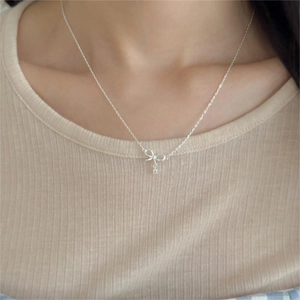 Detail shot of a silver bow necklace with zircon accents worn by a model on neck