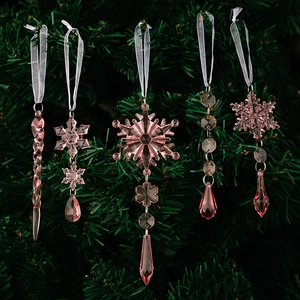 Close-up of pink acrylic snowflake and icicle ornaments on green Christmas tree branches