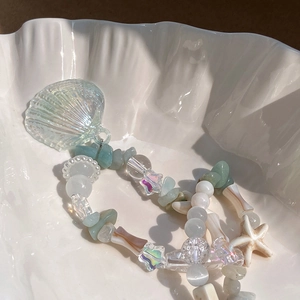 Macro detail of star beads and iridescent shell pendant on a marine-style necklace