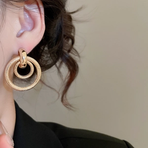 Gros plan détaillé des boucles d'oreilles anneau doré avec texture en métal poli et givré