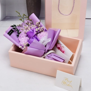 Detail of purple soap flower bouquet with roses, pink gift box and greeting card