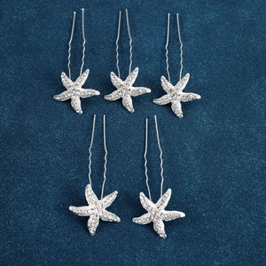 Detailed close-up of crystal starfish hair pins on premium navy velvet background