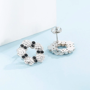 Macro view of black and white rhinestone flower wreath stud earrings with silver plating