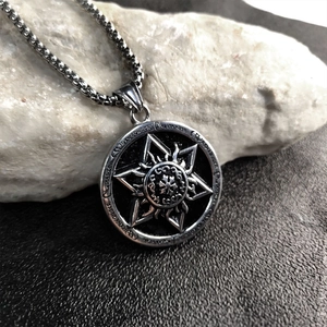Silver stainless steel Horus sun star pendant necklace on a rugged stone display base