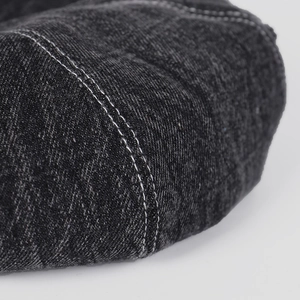 Detailed macro view of dark denim beret edge with contrast white double stitching