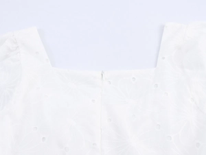 Détail du col carré et de la broderie anglaise délicate sur la robe blanche