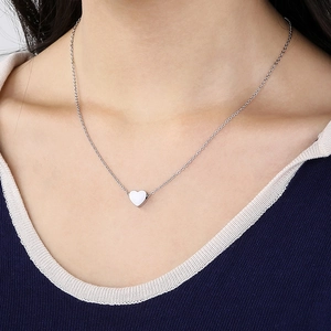 Nahaufnahme einer minimalistischen silbernen Herzkette am Hals einer Frau