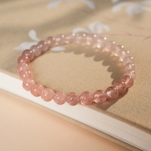 Macro detail of pink strawberry quartz beads on a minimalist beaded bracelet