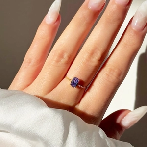 Detail of adjustable gold ring featuring an oval purple zircon on a delicate chain