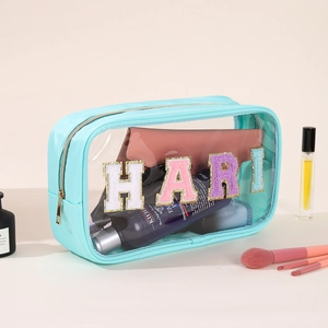Detail of teal PVC toiletry bag with glitter chenille HARI patch and gold zipper