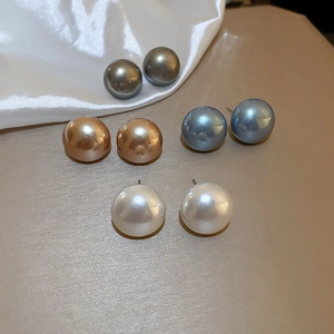 Detail showing four pairs of polished round pearl stud earrings in various elegant colors