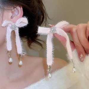 Close-up of pink ribbon bow earrings with snowflake detail and hanging pearl drops