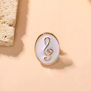 Close-up of elegant oval brooch with a golden G-clef on a white enamel background