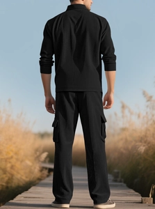 Outdoor back view of men's black corduroy tracksuit showing ribbed texture and cargo pants