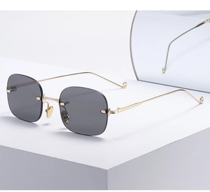 Close-up of rimless grey sunglasses with sleek gold metal temples and detail on tips