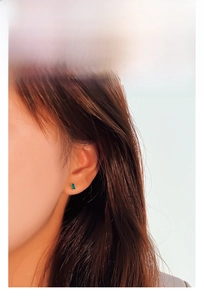 Close-up of model wearing small rectangular emerald green zircon stud earrings