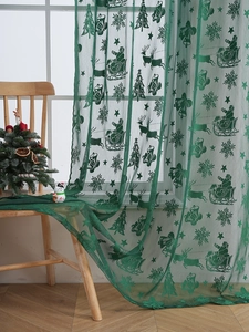 Détail du rideau de Noël en dentelle vert forêt avec motifs de Père Noël et rennes