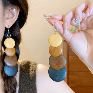 Detail of long geometric earrings with multi-colored round resin discs and wood grain texture