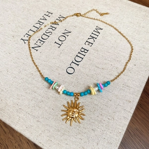 Close-up of golden sun pendant necklace with blue beads and sea shell fragments