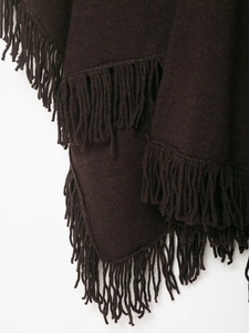 Detailed view of the dark coffee knitted texture and soft hanging fringe on the poncho