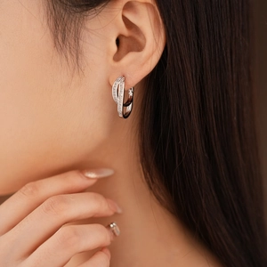 Close-up of double layer crisscross silver earrings with cubic zirconia on model