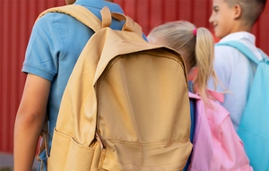 Detail of a large khaki canvas backpack with zippered front pocket for school use