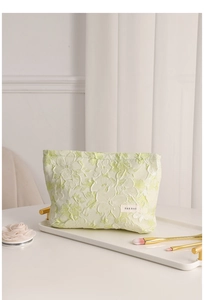 Close-up of light green floral jacquard makeup bag with cosmetic brushes on a tray