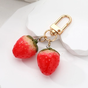 Close-up of realistic resin strawberry pendants with detailed textures and gold metal clasps
