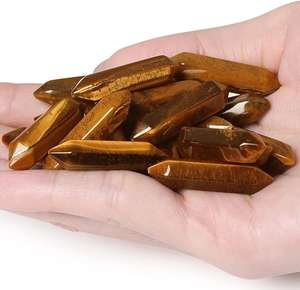 Close-up of hand holding natural tiger eye crystal double point hexagonal columns