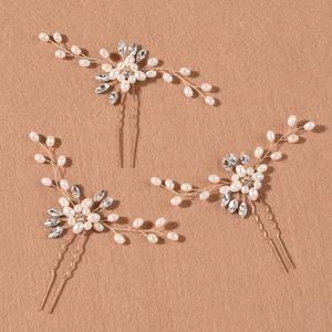 Dettaglio di tre forcine dorate per capelli con perle bianche e strass scintillanti