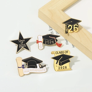 Detailed view of five black and white 2026 graduation enamel pins with gold plating