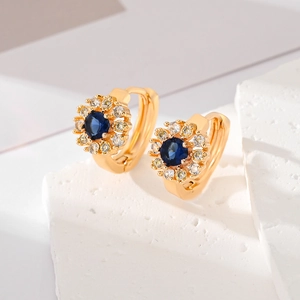Macro shot of sunflower earrings with deep blue zircon and white diamonds on gold base