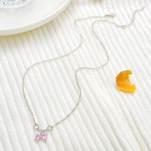 Detalle de un collar de plata con piedras de circonita rosa en forma de cereza