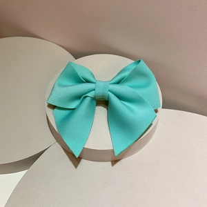 Detail of mint green ribbed ribbon bow hairclip on white minimalist display stand