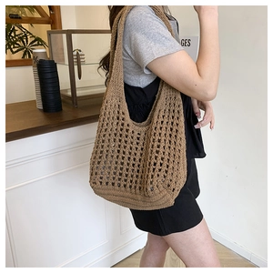 Detail of a brown crochet tote bag with woven flower patterns shown on a shoulder