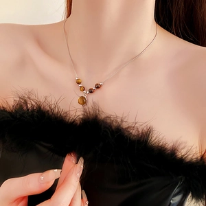 Close-up of a brown tiger eye bead pendant necklace worn on a black feather top