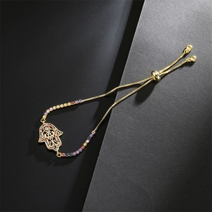Gros plan du bracelet main de Fatma doré avec zircons colorés et chaîne ajustable