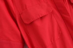 Detailed close-up of red poplin dress showing stitching on pockets and smooth fabric texture
