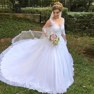 Elegant white lace wedding dress with long sleeves and cathedral train on outdoor lawn