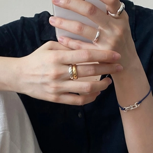 Detailed view of sterling silver rings with quilted texture and a woven navy bracelet