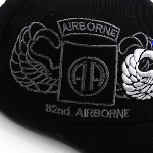 Detailed close-up of 82nd Airborne Division grey embroidery on a black cotton baseball cap